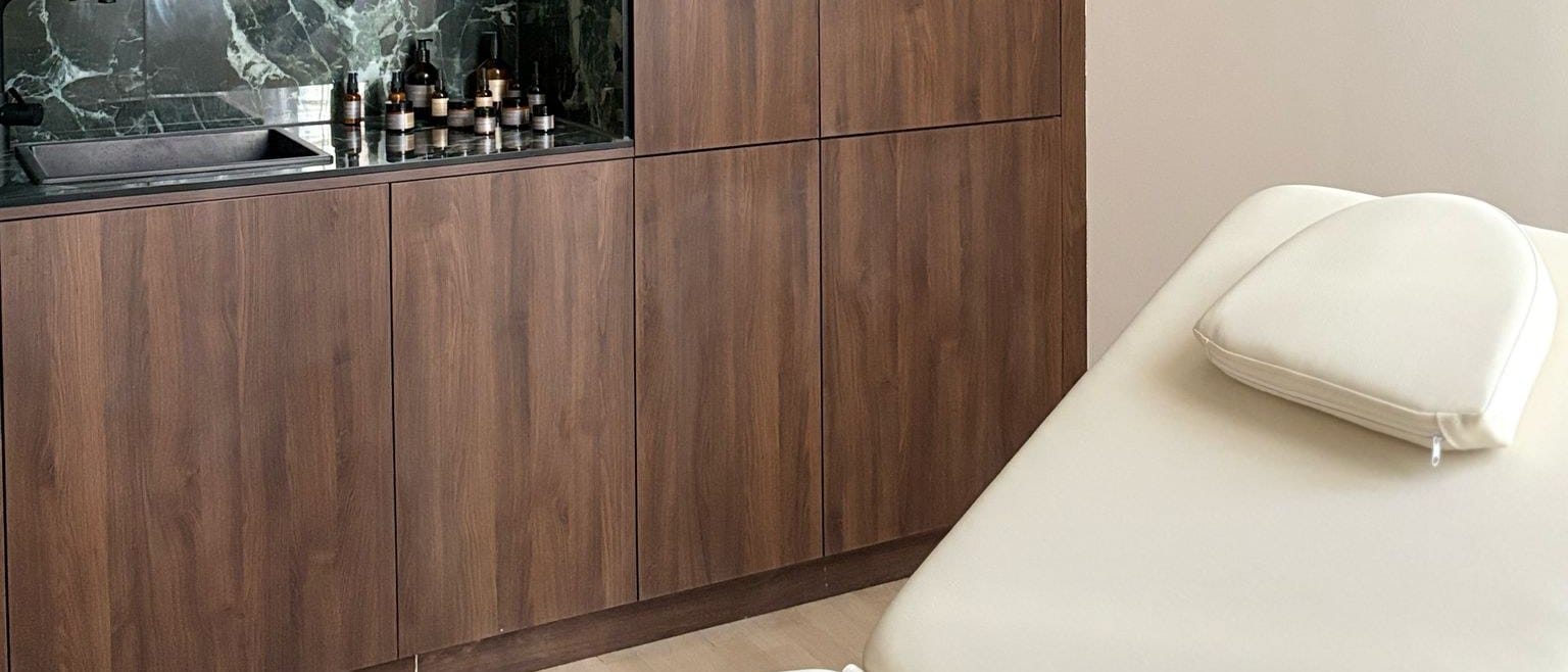 Behandlungsraum bei The Retreat Berlin mit Liege, Walnussholz und grünem Onyx